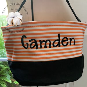 May include: Orange and white striped Halloween trick-or-treat bag with a black bottom and a black embroidered name "Camden".