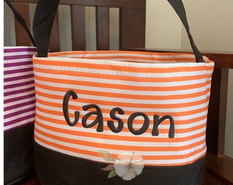 May include: Orange and white striped Halloween trick-or-treat bucket with black handles and a black bottom. The bucket is personalized with the name "Gason" in black embroidery.