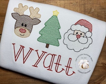 May include: Embroidered Christmas design on a white shirt featuring a reindeer, a Christmas tree, Santa Claus, and the name Wyatt.