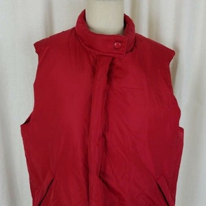 May include: A red sleeveless puffer vest with a zipper closure and a button at the top.