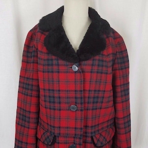 May include: A red and black plaid coat with a black faux fur collar. The coat has a button closure and two pockets.