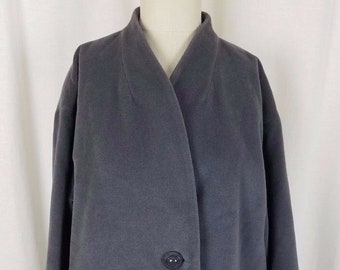 May include: A charcoal gray coat with a notched collar and two dark buttons. The coat has two front pockets and a long, streamlined silhouette. The fabric appears to be a soft, medium-weight material.