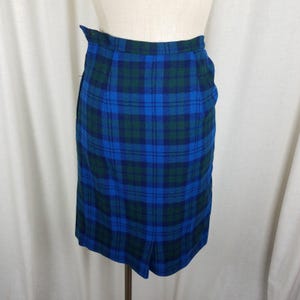 May include: A blue and green plaid skirt with a straight silhouette. The skirt has a zipper closure and a back vent.
