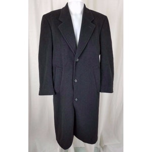 May include: A long black wool overcoat with a classic design, featuring a notched collar, three button closure, and flap pockets.