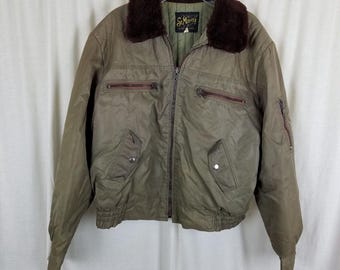 May include: A green bomber jacket with a brown faux fur collar. The jacket has a zipper closure and multiple pockets. The label on the jacket reads "St. Moritz".