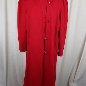 May include: A long, red wool coat with a mandarin collar and five large red buttons down the front.