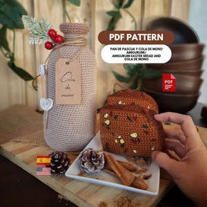 Puede incluir: Patrón de crochet para un pan de Pascua español tradicional y una botella de cola de mono. El patrón está disponible para descargar en PDF. La imagen muestra una botella de crochet con una etiqueta que dice "Cola de mono" y un pan de crochet con chispas verdes y rojas.