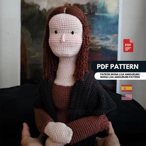 Op de afbeelding: Gehaakte pop die de Mona Lisa voorstelt, met een lichtbeige gezicht, roze wangen, bruin haar en een zwarte jas. De afbeelding bevat een PDF-patroon. De tekst op de afbeelding luidt "PDF PATTERN" en "PATRÓN MONA LISA AMIGURUMI/ MONA LISA AMIGURUMI PATTERN".