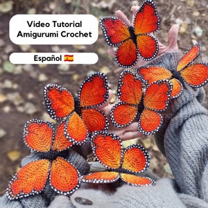 Puede incluir: Cinco mariposas de crochet naranja y negro con detalles blancos. Las mariposas están en la mano de una persona. La imagen incluye el texto "Video Tutorial Amigurumi Crochet Español"