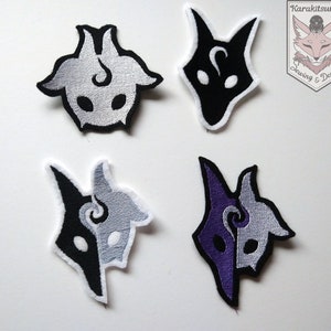 以下が含まれることがあります： 狼のマスクのデザインが施された、アイロン接着式の刺繍パッチが4つ。2つのパッチは白黒、1つは紫と白、もう1つは黒一色です。