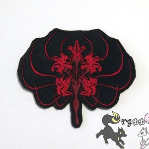May include: Black felt patch with a red embroidered design of a stylized flower with multiple petals. The flower is surrounded by a black outline.