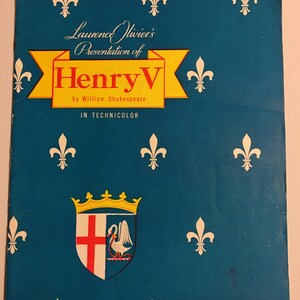 May include: A blue and yellow program for a presentation of Henry V by Laurence Olivier in Technicolor. The program features a coat of arms with a white swan and a red cross on a white background.