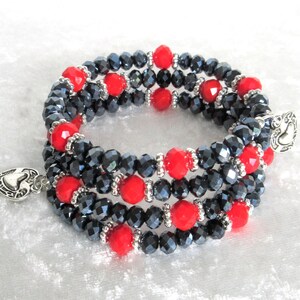 May include: A multi-strand bracelet featuring faceted black beads interspersed with vibrant red beads. The bracelet has a silver-toned heart-shaped clasp and decorative accents. This jewelry piece is suitable for everyday wear or special occasions.