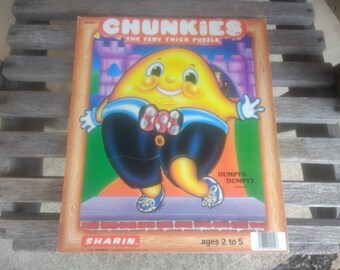 May include: A yellow cartoon character with a red bow tie and blue shoes. The character is wearing blue pants and is standing on a brick walkway. The puzzle is called "Chunkiest The Very Thick Puzzle" and features the character Humpty Dumpty. The puzzle is for ages 2 to 5.