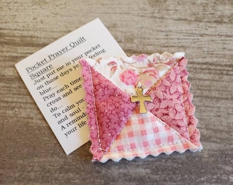 May include: A pink and white quilted square with a gold cross charm. The square has a scalloped edge and is made of different fabrics. The text on the card reads "Pocket Prayer Quilt Square Just put me in your pocket on those days you blue... Pray each time cross and see do... To calm you and soul A remind your life feeling"