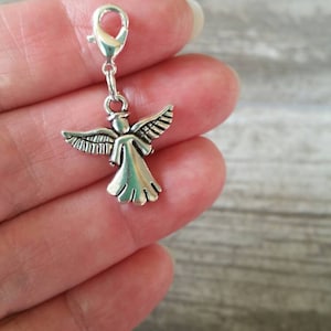 Puede incluir: Encanto de ángel de plata con un bucle para sujetarlo a un collar o pulsera. El ángel tiene alas y un diseño simple.