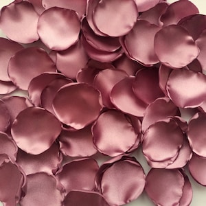 以下が含まれることがあります： ダスティローズ色のサテン生地で作られたバラの花びらの山