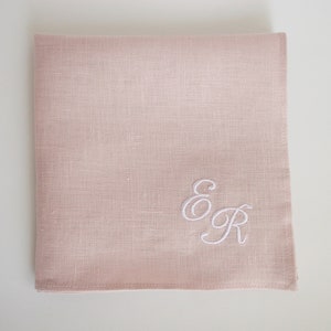 May include: A pale pink linen handkerchief with white embroidered initials "E & R" in a cursive script.