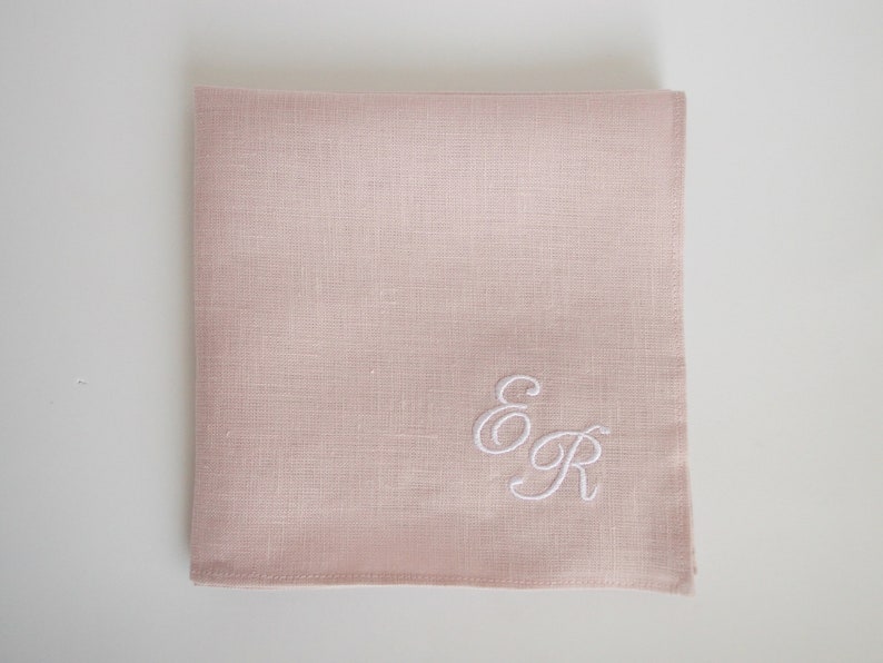 May include: A pale pink linen handkerchief with the embroidered initials "E & R" in white.