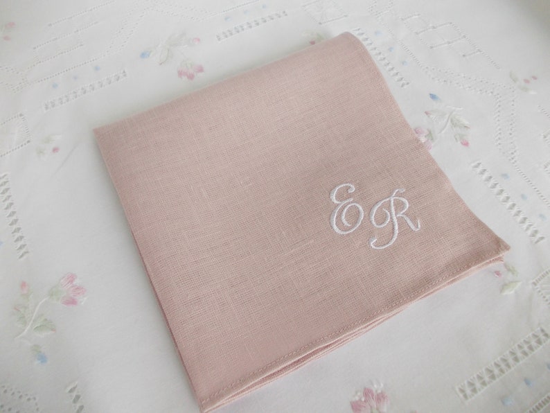 May include: A pale pink linen handkerchief with the embroidered initials "E & R" in white thread.