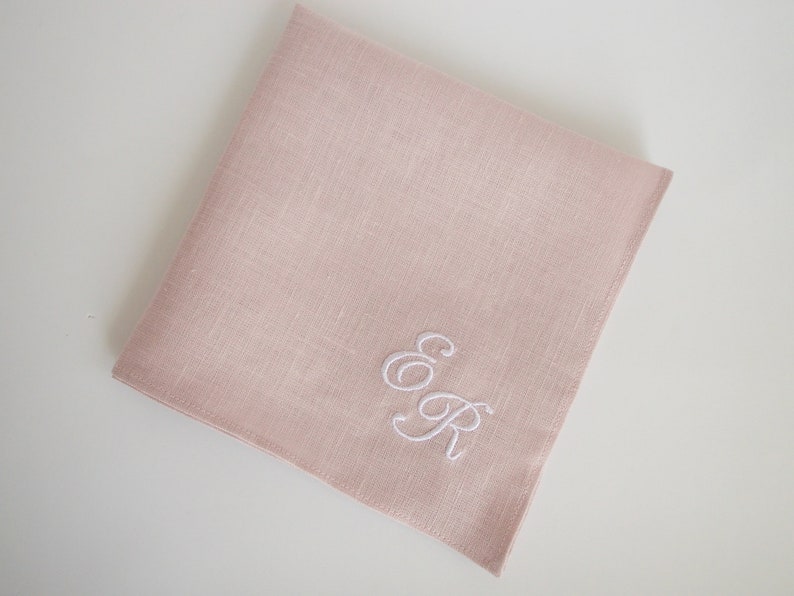 May include: A pale pink linen handkerchief with white embroidered initials "E & R".