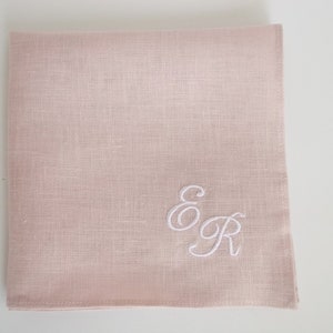 May include: A pale pink linen handkerchief with white embroidered initials "E & R" in a cursive script.