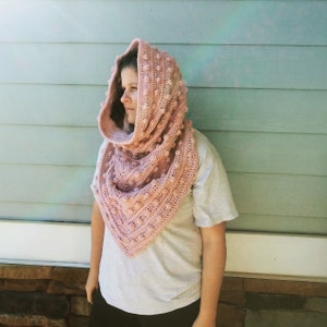 May include: A pink crocheted cowl with a hood and a textured bobble stitch pattern.