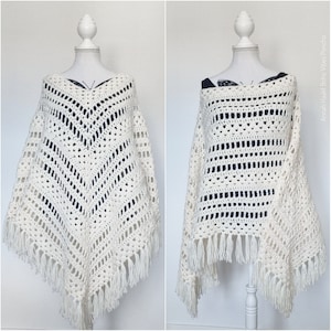 Op de afbeelding: Wit gebreid poncho met franjes op een wit mannequin. De poncho heeft een geometrisch patroon en wordt in twee verschillende stijlen getoond.