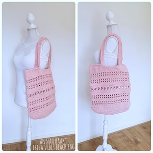 Op de afbeelding: Een roze gebreide tote bag met een "Ibiza Vibes Beach Bag" label. De tas heeft een breipatroon met open ruimtes.
