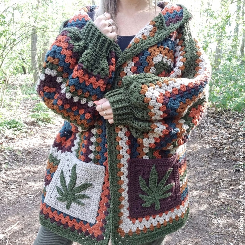 May include: A green, brown, and orange crochet cardigan with a hood and two pockets featuring a green marijuana leaf design.