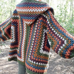 May include: A crocheted cardigan with a hood in shades of brown, green, beige, and blue. The cardigan has a granny square pattern and is open in the front.