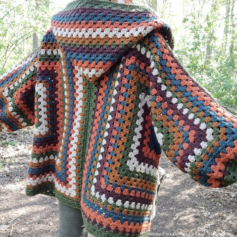 May include: A crocheted cardigan with a hood in shades of brown, green, beige, and blue. The cardigan has a granny square pattern and is open in the front.