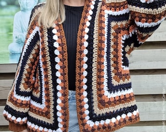 Peut inclure: Un cardigan en crochet marron, beige, blanc et noir avec un motif carré. Le cardigan a une longue ouverture sur le devant et des manches longues.