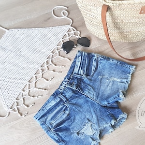 Op de afbeelding: Een wit gehaakt topje met franjes en een blauwe denim short met distressed details. De tekst "ANNAH HAAKT EZ BOHO BEACH TOP" is zichtbaar in de afbeelding.