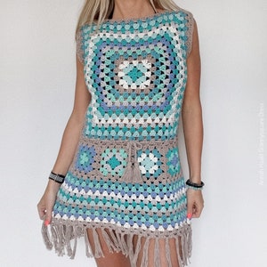 May include: A handmade crochet dress in a granny square design. The dress is sleeveless and features a colour palette of teal, blue, grey, and white, with a fringed hem and a matching belt with a tassel. The dress is approximately knee-length.