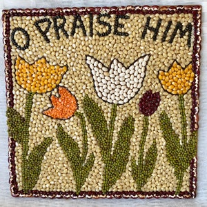 May include: A square artwork made of various beans and seeds, depicting a floral arrangement with the words "Praise Him" at the top.