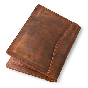 May include: A brown leather notebook with a stitched edge and the word "PEGASI" embossed on the front.