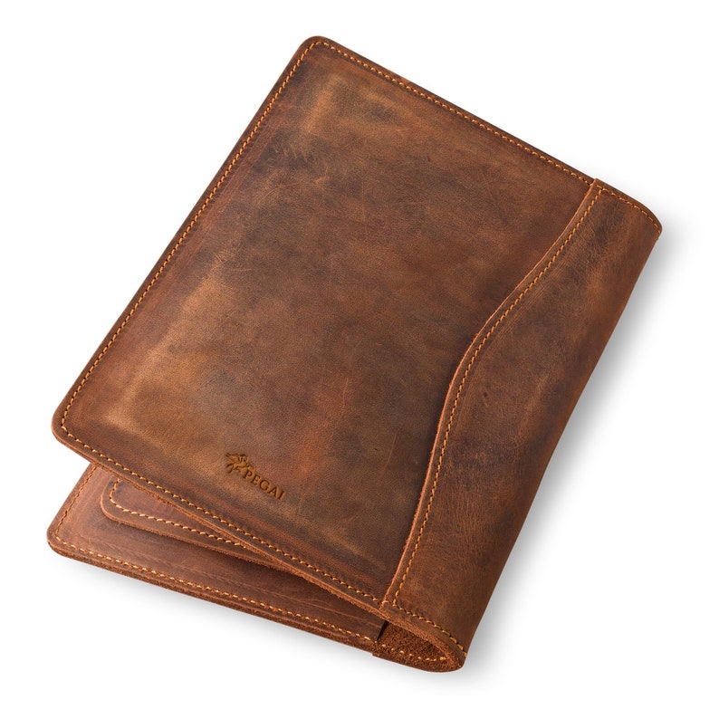 May include: A brown leather notebook with a stitched edge and the word "PEGASI" embossed on the front.