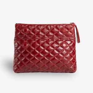 Op de afbeelding: Een gestikte clutch van bordeauxrood leer met een ritssluiting en een kwast.