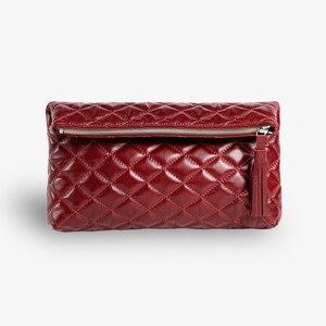 Op de afbeelding: Een bordeauxrode quilted leren clutch met een zilveren rits en een kwast.