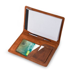 May include: A brown leather portfolio with a notepad, pen holder, and a pocket for a visitor guide. The guide has the text "Visitor Guide" on the cover.