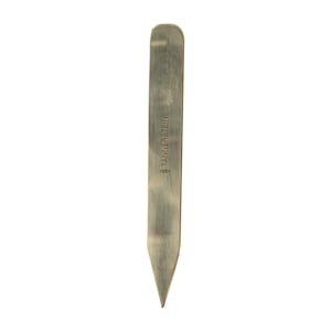 May include: A silver metal collar stay with a pointed tip and the inscription "TANNERS TEIN" on the side.