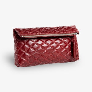 Op de afbeelding: Een bordeauxrode quilted leren clutch met een ritssluiting en een kwast.