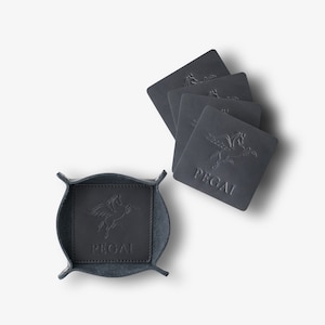 May include: Set of five black leather coasters with a winged horse design and the word "PEGASI" embossed on each. The coasters are in a black leather tray with the same design.