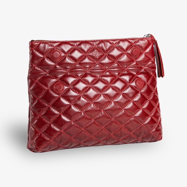 Op de afbeelding: Een gestikte rode leren clutch met een ritssluiting en een kwast.