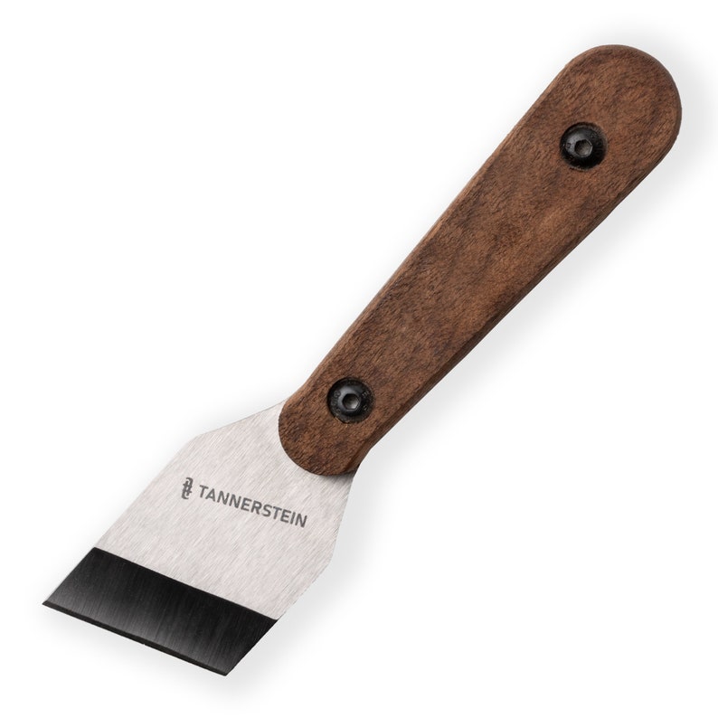Op de afbeelding: Een kleine schraper met een bruin houten handvat en een zwart en zilveren blad. Het blad is gemarkeerd met "TANNERS TEIN".
