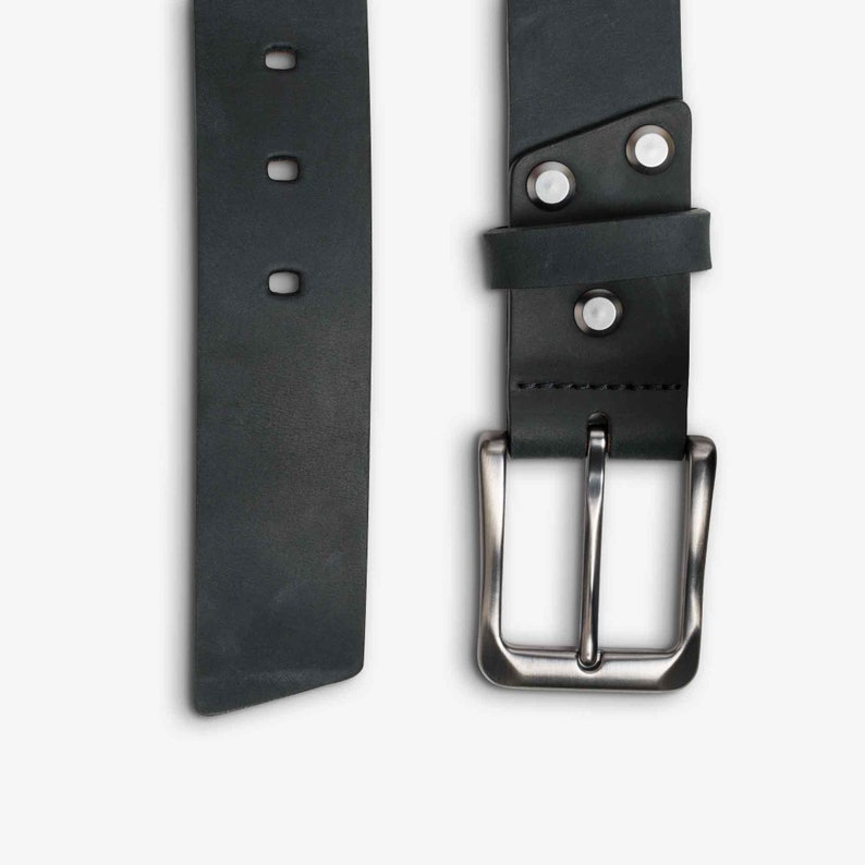 May include: A black leather belt with a silver buckle. The belt has three rows of stitching and a smooth, matte finish.