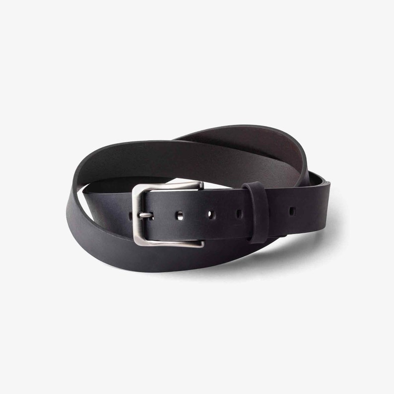 May include: A black leather belt with a silver buckle. The belt is rolled up and the buckle is visible.