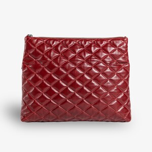 Op de afbeelding: Een gestikte clutch van bordeauxrood leer met een ritssluiting.
