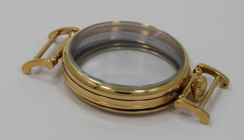 May include: Gold-tone watch case with a clear glass face and a hinged strap.
